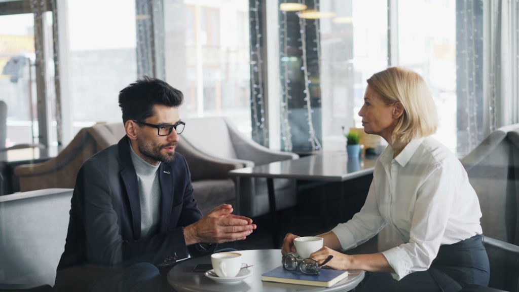 Two professionals in conversation at a table, discussing outreach strategy
