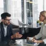 Two professionals in conversation at a table, discussing outreach strategy