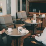 Two professionals having a warm one-on-one conversation at a cafe, illustrating a warm-first LinkedIn outreach strategy