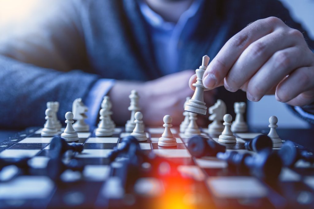 A person considering their next move over a chess board, a metaphor for deciding whether LinkedIn Sales Navigator is worth the investment.