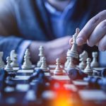 A person considering their next move over a chess board, a metaphor for deciding whether LinkedIn Sales Navigator is worth the investment.