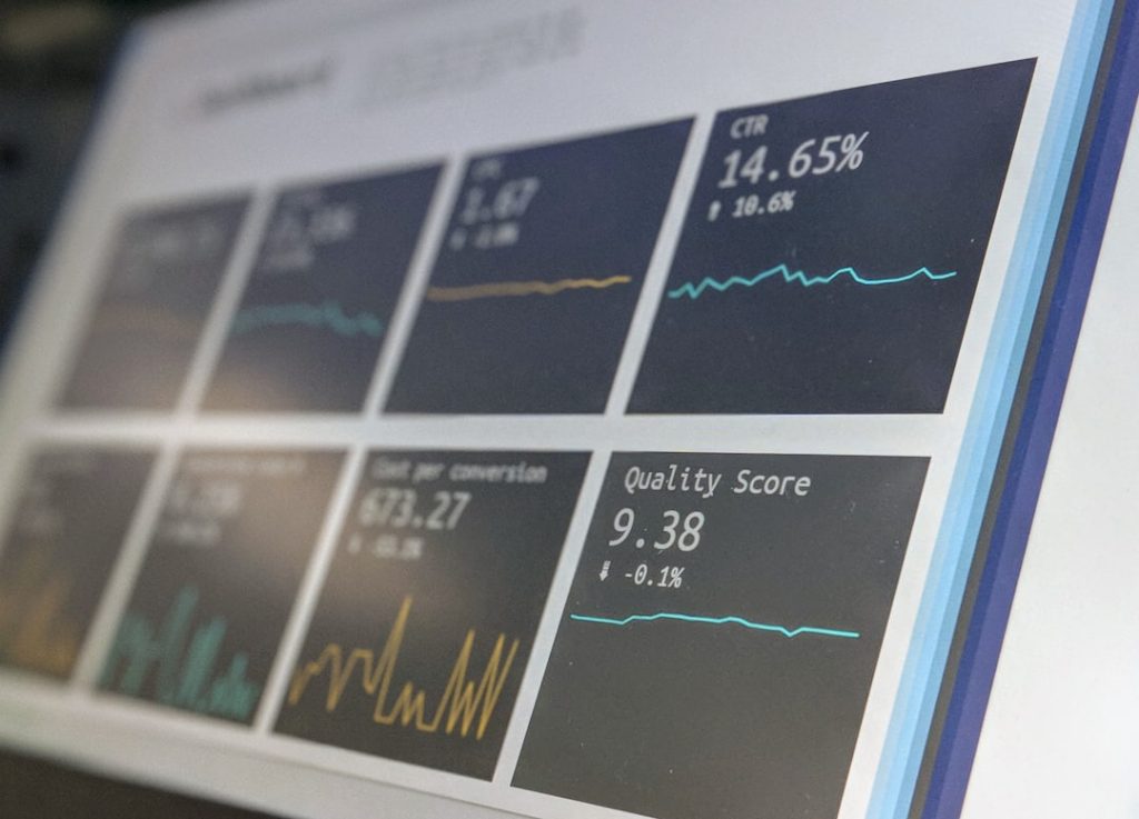 A wall-mounted monitor displaying live analytics charts and performance metrics, the kind of cadence reporting dashboard a sales engagement platform puts in front of a sales manager.